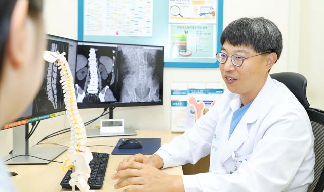 NSP통신-박재우 교수가 척추질환을 호소하는 환자에게 설명하는 모습. (사진 = 강릉아산병원)