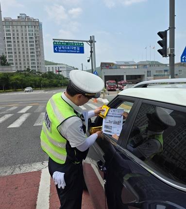 NSP통신-무안경찰서 관계자들이 출근 시간대 관내 주요 교차로에서 운전자들에게 물티슈 및 치안 소식지를 배포하며 교통 기초질서 준수 계도활동을 펼치고 있다. (사진 = 무안경찰서)