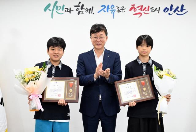 NSP통신-이민근 안산시장(가운데)이 선행을 실천한 성호중학교 양시온, 유호현 학생에게 표창장을 수여하고 함께 기념촬영을 하고 있다. (사진 = 안산시)