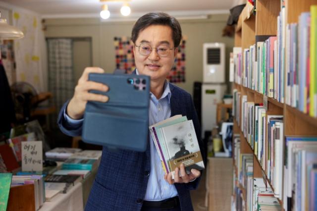 NSP통신-수원의 지역 서점인 광화문 서림을 방문한 김동연 경기도지사가 민생회복 소비쿠폰으로 여러권의 책을 구입 후 셀카를 찍고 있다. (사진 = 경기도)