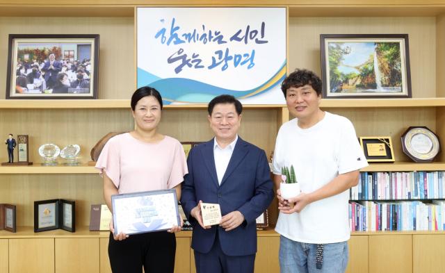 NSP통신-박승원 시장이 21일 오전 시장실에서 1만 5000번째 1.5℃ 기후의병 가입자 최 모 씨를 만나 기념패를 전달하고 기념사진을 촬영하고 있다. 사진 왼쪽부터 1.5℃ 기후의병 가입자 최 모 씨, 박승원 광명시장, 최 모 씨의 남편. (사진 = 광명시)