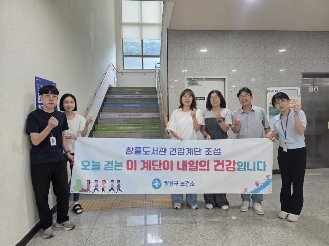 NSP통신-창룡도서관에 조성한 건강계단 앞에서 팔달구보건소 직원들이 기념촬영을 하는 모습. (사진 = 수원시)