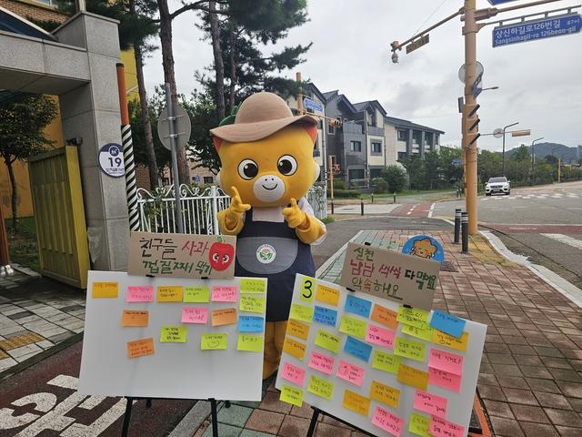 NSP통신-18일 화성시 마스코트 코리요가 향남유치원 앞에서 어린이들과 학부모들을 대상으로 환경친화적 저탄소 식문화 캠페인을 하는 모습. (사진 = 화성시)