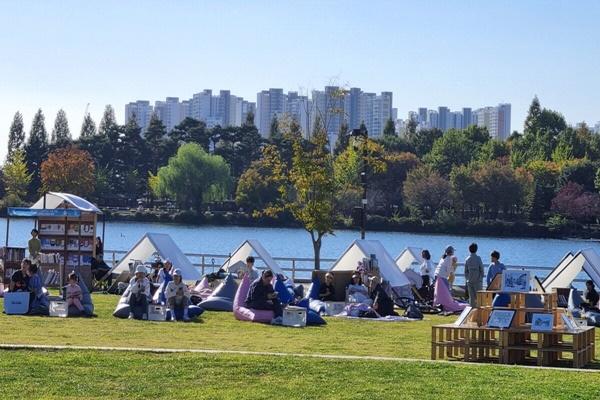 NSP통신-호숫가 잔디밭 야외도서관에서 책을 읽는 시민들(2024 독서대전) (사진 = 고양시)
