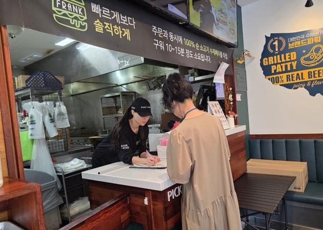 NSP통신-성남시 어린이 기호식품 전담관리원이 지난 9월 학교 주변 햄버거 판매점에서 영업자와 종업원의 건강진단 실시 여부를 점검하고 있다. (사진 = 성남시)