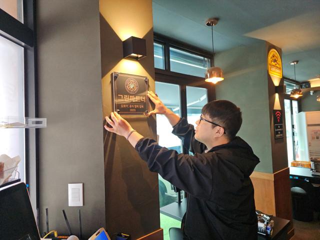 NSP통신-장진석 대표가 매장 내 현판을 부착하고 있는 모습. (사진 = 김포FC)