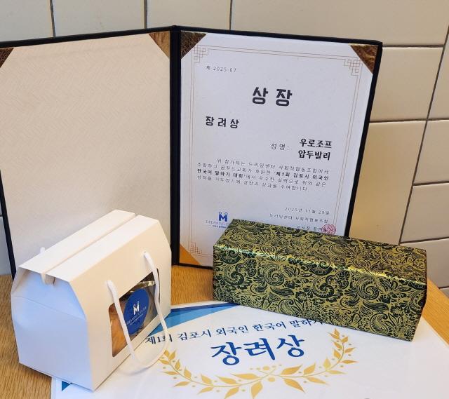 NSP통신-김포대학교 한국어과정에 재학중인 타지키스탄 출신 학생이 제1회 김포시 외국인 한국어 말하기 대회에서 장려상을 수상했다. 사진은 압두발리 학생이 수상한 상장과 상품. (사진 = 김포대학교)