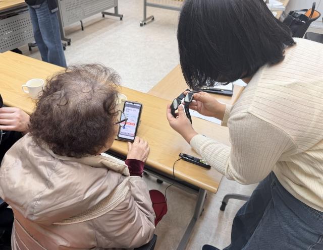 -치매예방 스마트 건강케어 사업에 참여하는 어르신에게 스마트워치 사용법을 설명하고 있다 사진 광명시