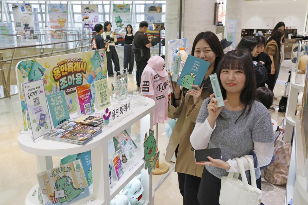 -외국 관광객이 서울 롯데면세점 월드타워점 9층에서 열린 ‘K-공공캐릭터 굿즈 팝업존’에서 용인특례시 대표 캐릭터 조아용 굿즈를 들고 기념촬영을 하고 있다. (사진 = 용인특례시)