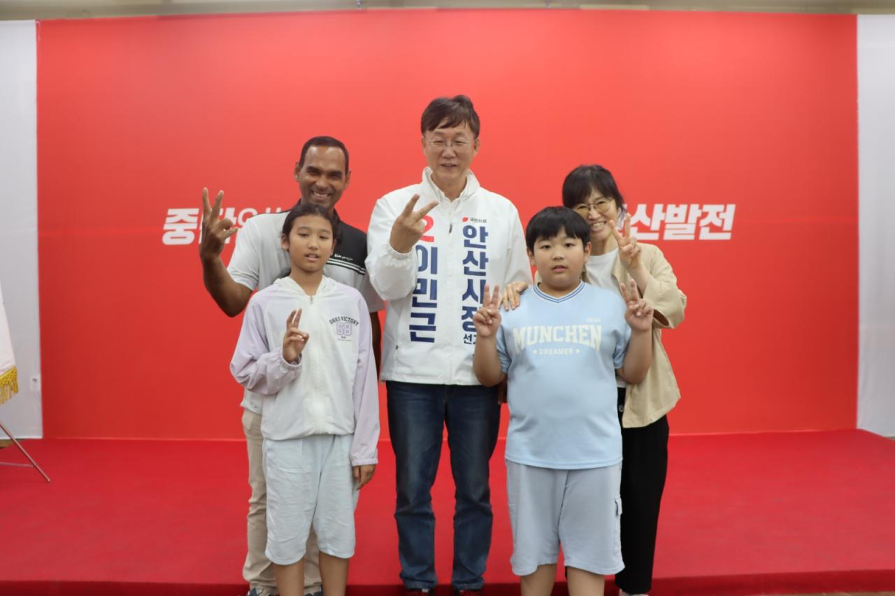 -이민근 안산시장 후보가 캠프에서 이민청 유치홍보활동한 가족(아빠 아지(인도), 엄마 영선(한국)과 자녀들)과 함께 사진촬영을 하고 있다. (= 이민근 안산시장 원팀캠프)