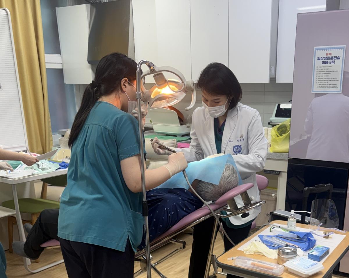 -김윤정 관악서울대학교치과병원 치주과 교수(오른쪽)가 광명장애인종합복지관 이용 장애인 대상으로 치과 치료를 진행하고 있다. (사진 = 광명시)