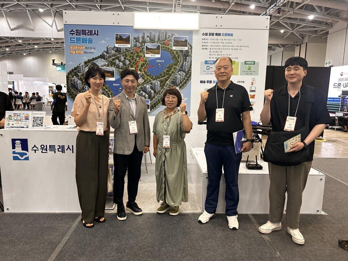 -수원시가 ‘2026 대한민국 드론·도심항공교통(UAM) 박람회’에서 운영중인 홍보부스에서 관계자들이 기념촬영을 하는 모습. (사진 = 수원시)